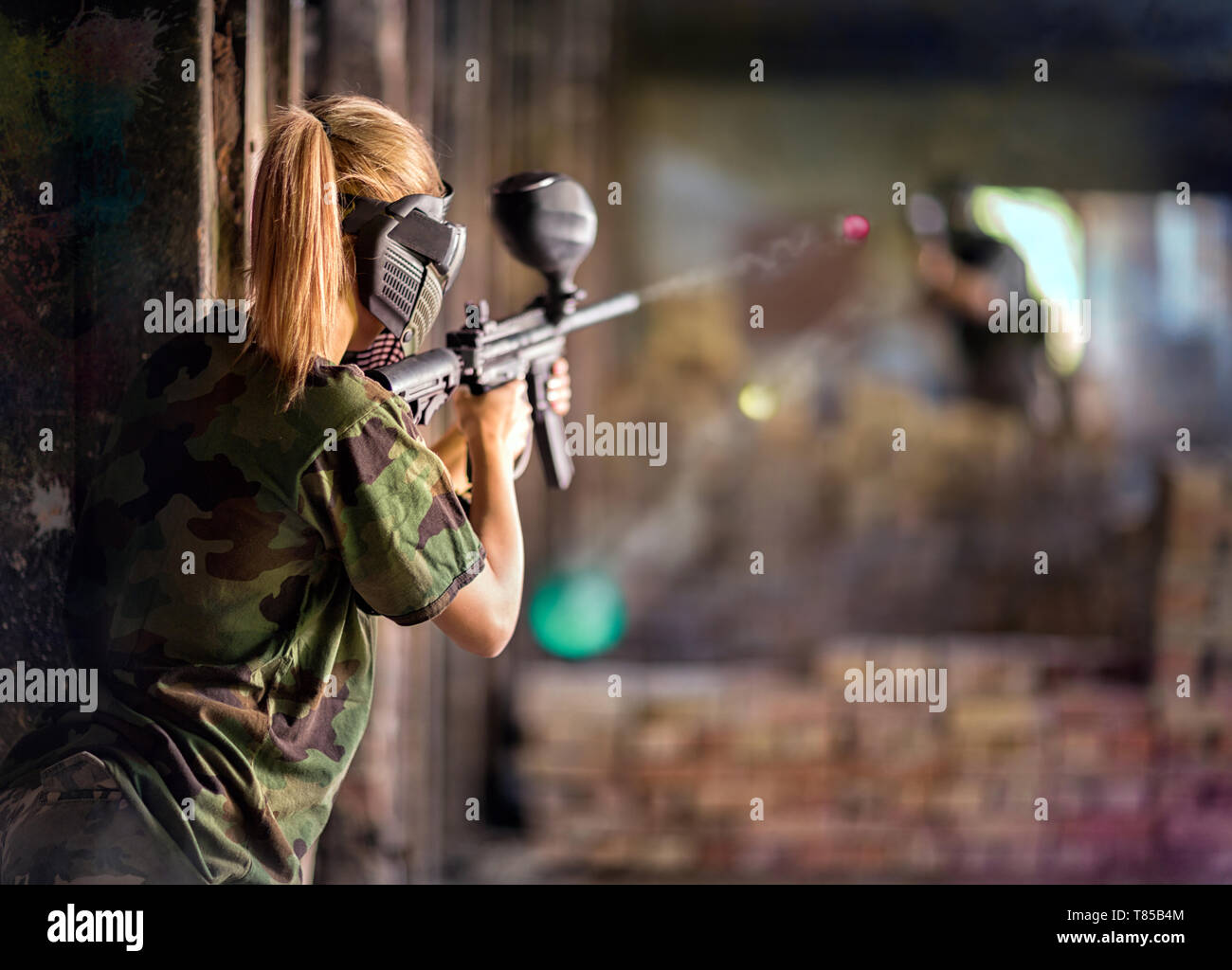 Paintball player in action behind cover during shootout Stock Photo Alamy