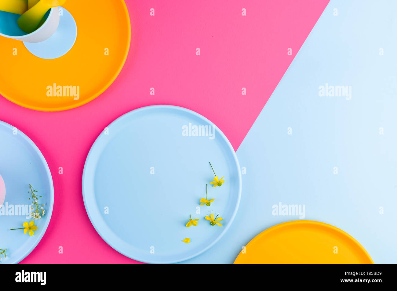 Multi-colored plastic picnic utensils on a pink background. Glasses and dinner plates. Flat lay. Copy space Stock Photo