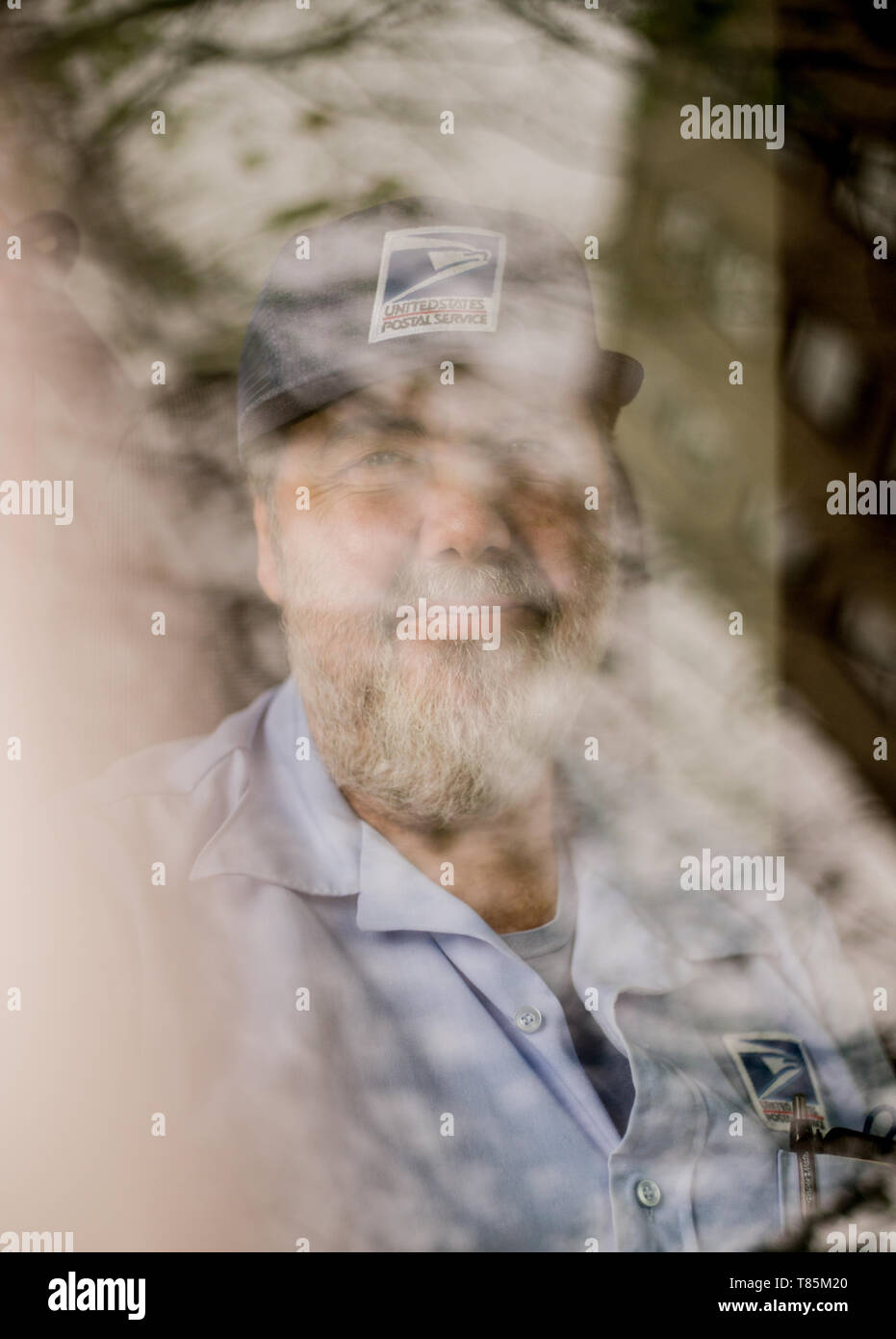 street portrait taken in Philadelphia Pennsylvania, of a United States Postal  delivery man photographed throuhg the window of his vehical Stock Photo