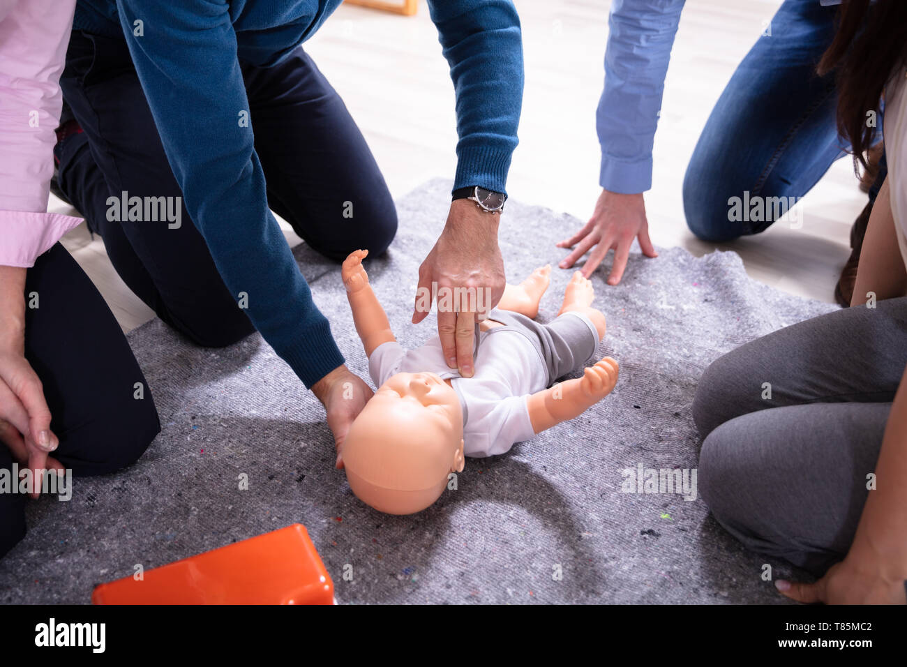 Specialist Giving Baby CPR Dummy First Aid Training To His Colleagues Stock Photo