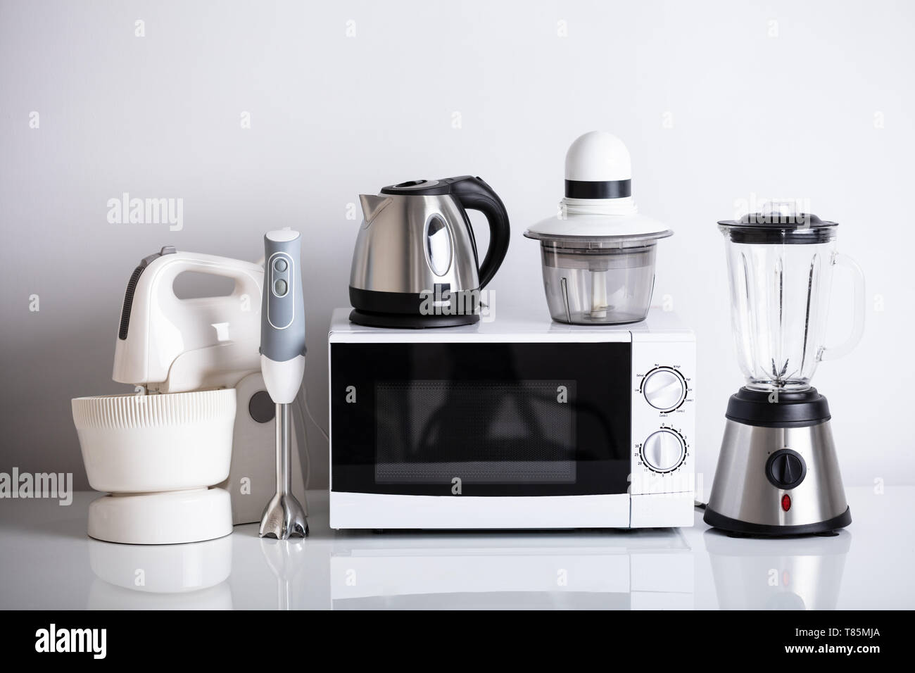 Variety Of Kitchen Appliances With Oven Over Reflective Desk Stock Photo