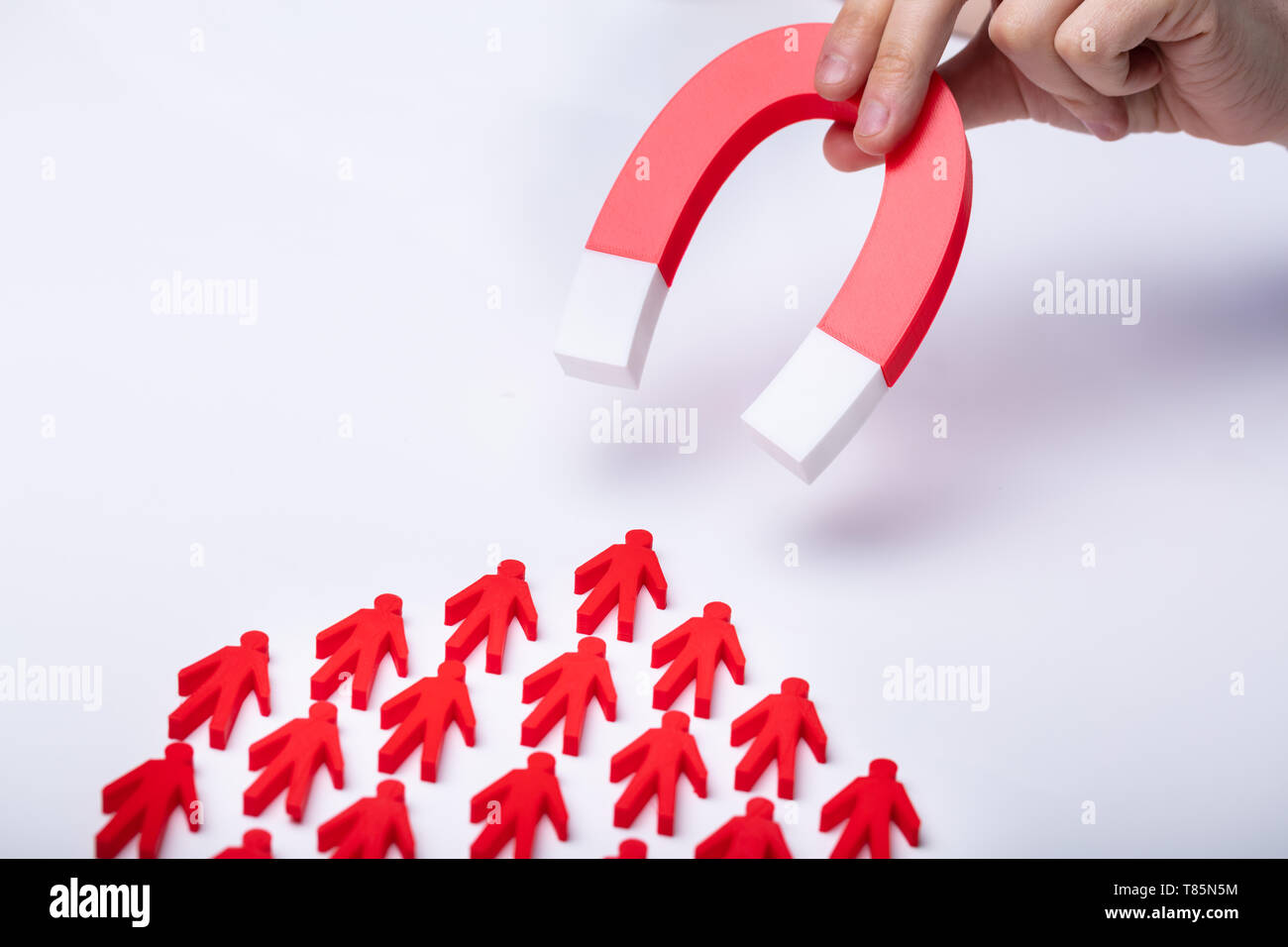 Businessman's Hand Attracting Red Team With Horseshoe Magnet On White Background Stock Photo