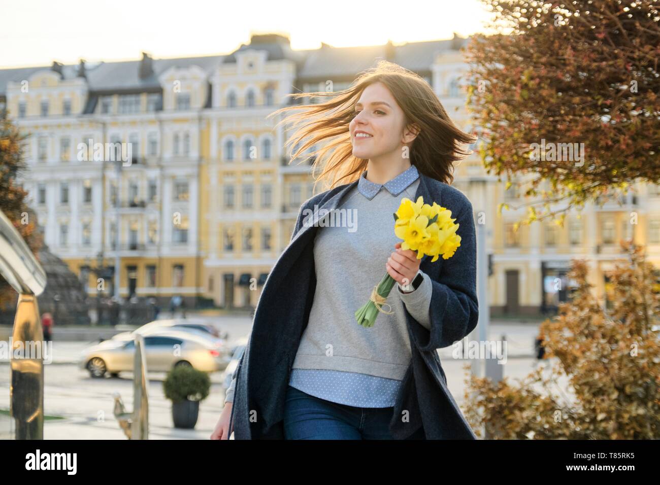 Outdoor portrait of young beautiful girl with bouquet of yellow spring ...