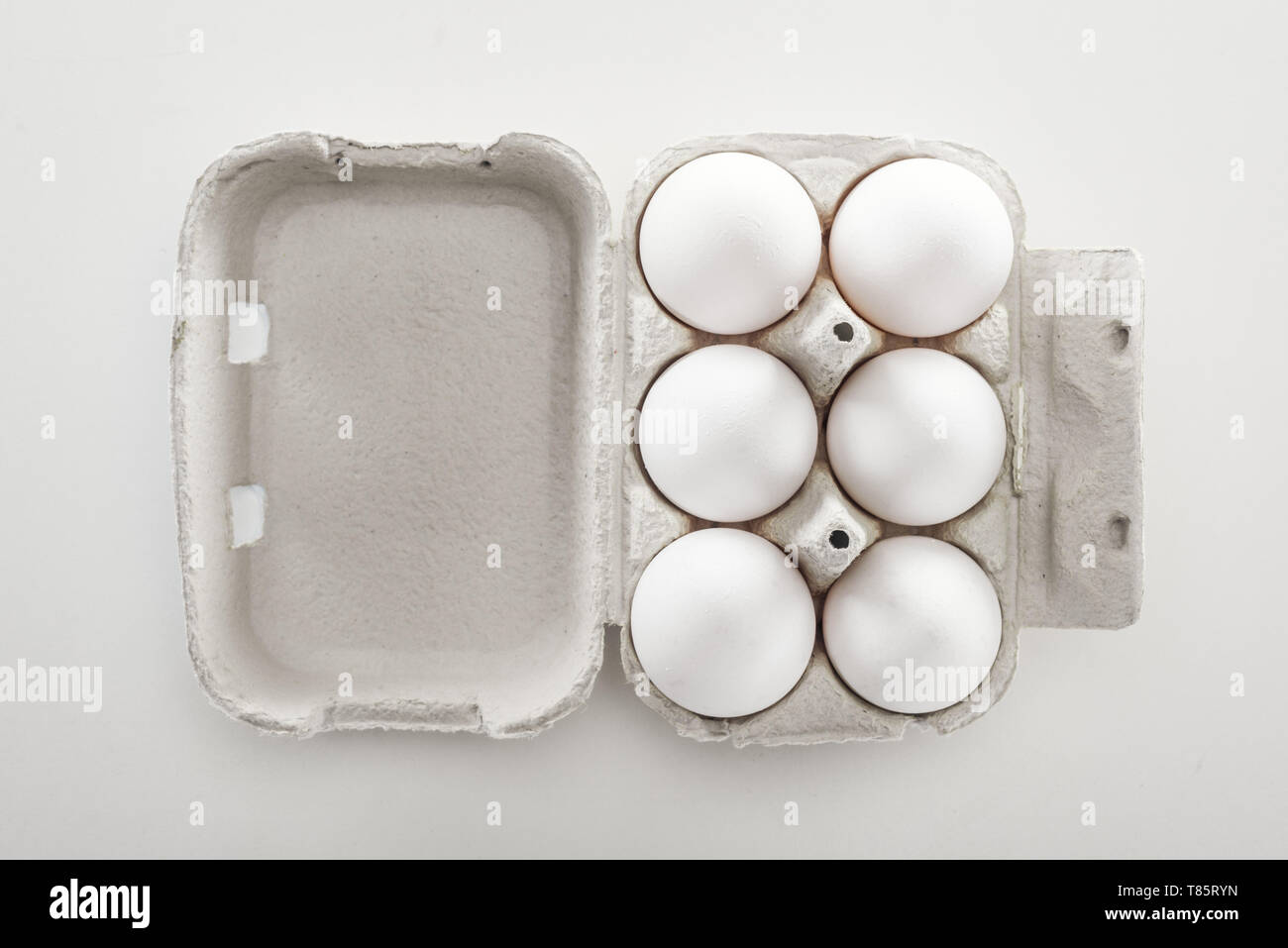 top view of raw white chicken eggs in carton box on white background ...