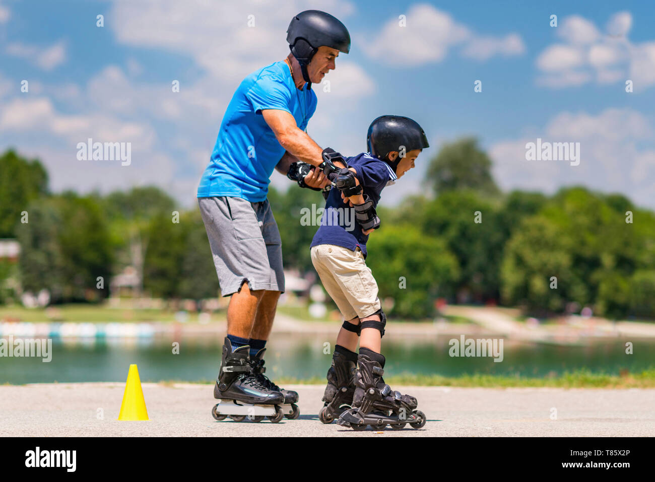 Grandfather teaching grandson to roller skate Stock Photo