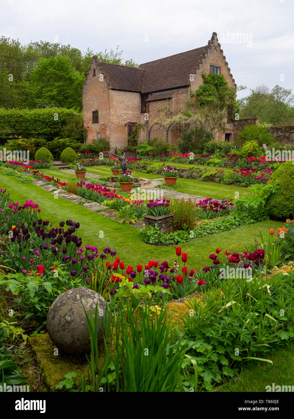 Chenies Manor Sunken Garden with Pavilion and pond in early May showing colourful tulips, sculpture and fresh green foliage beautifully landscaped. Stock Photo