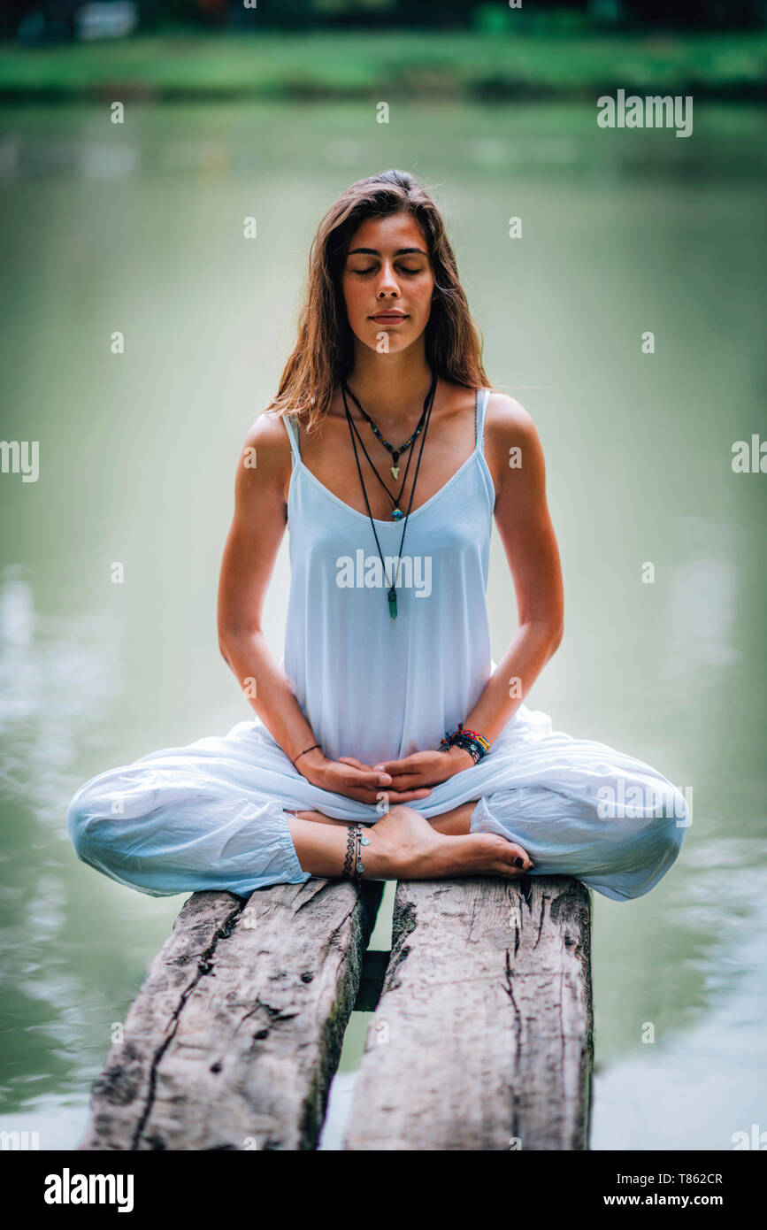 Woman meditating by a lake Stock Photo