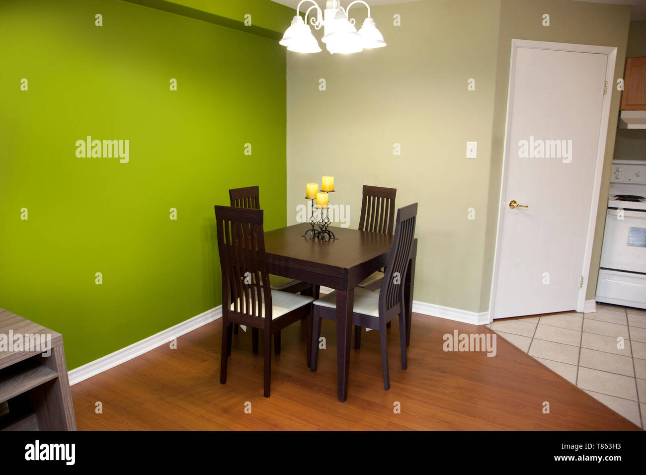 Green walls with a dark wood table and chair set for four in a kitchen or dining area of a home Stock Photo