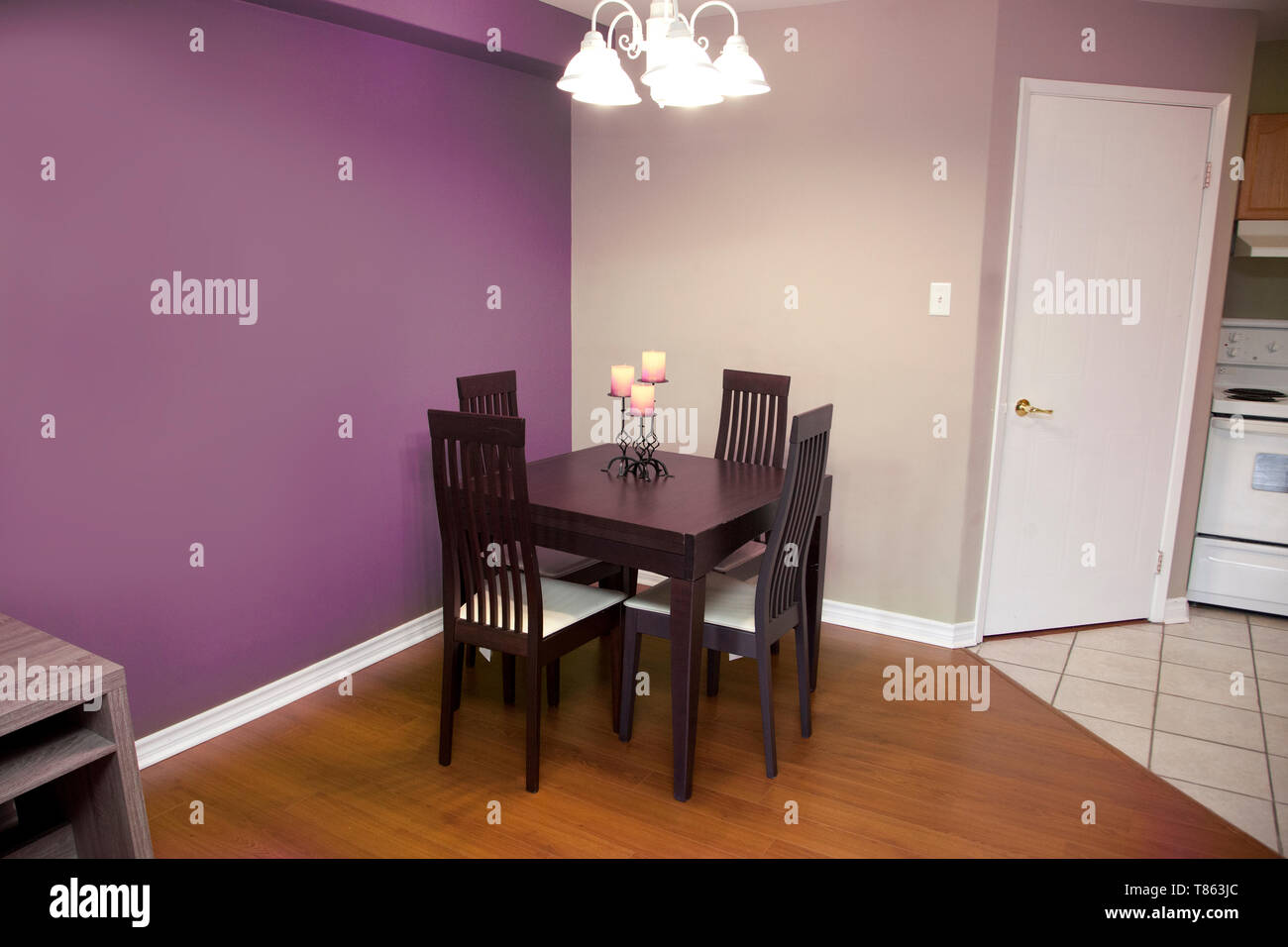 purple walls with a dark wood table and chair set for four in a kitchen or dining area of a home Stock Photo