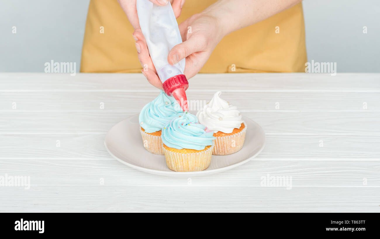 Cropped View Of Woman Decorating Cupcakes With Icing Bag Stock