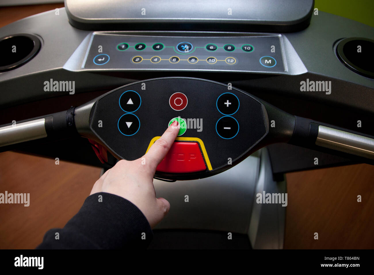 Get ready to run hand pushes the green start button on a treadmill in