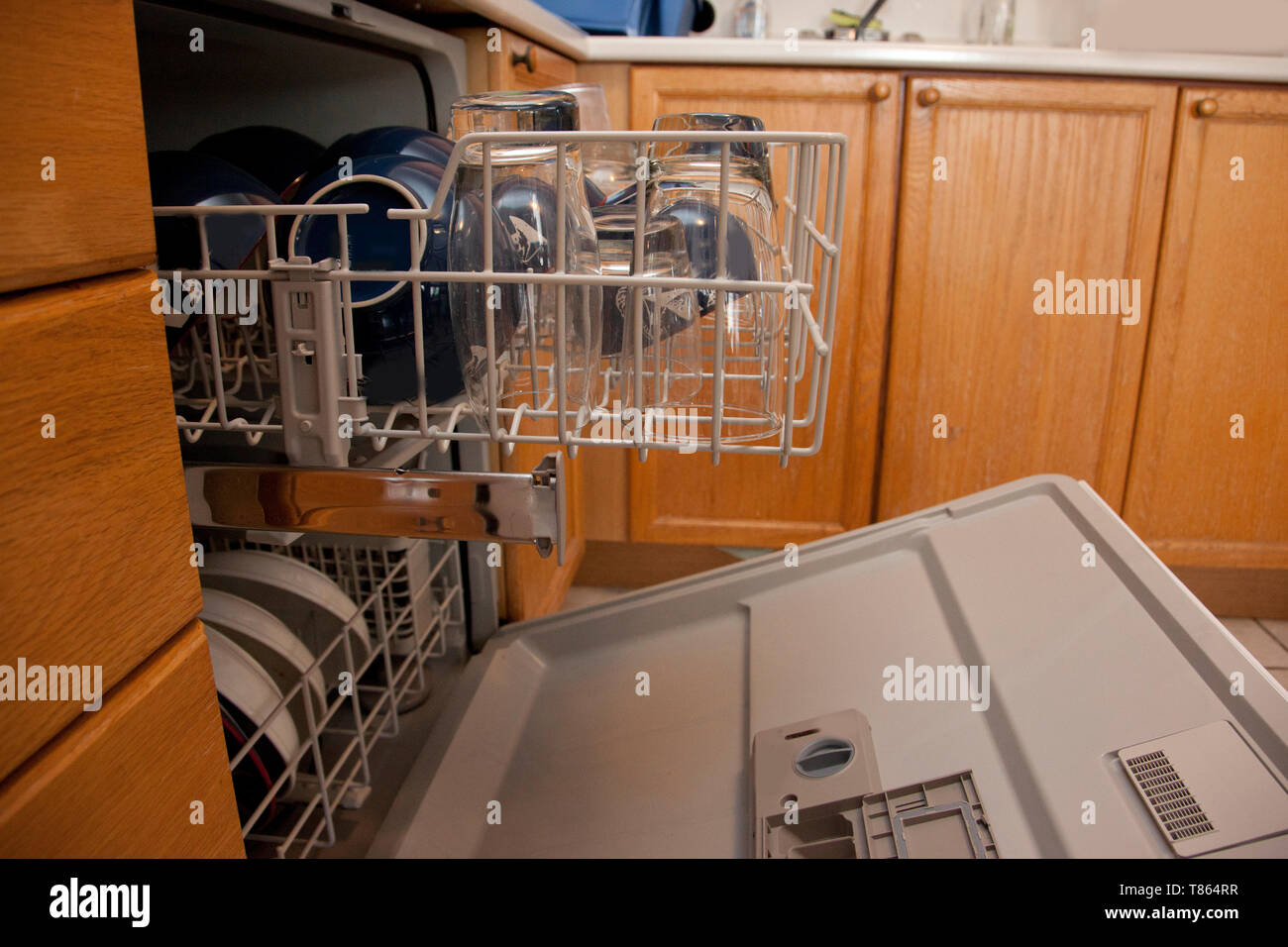 The top drawer of a dishwasher is full of bowls and glassware, in a
