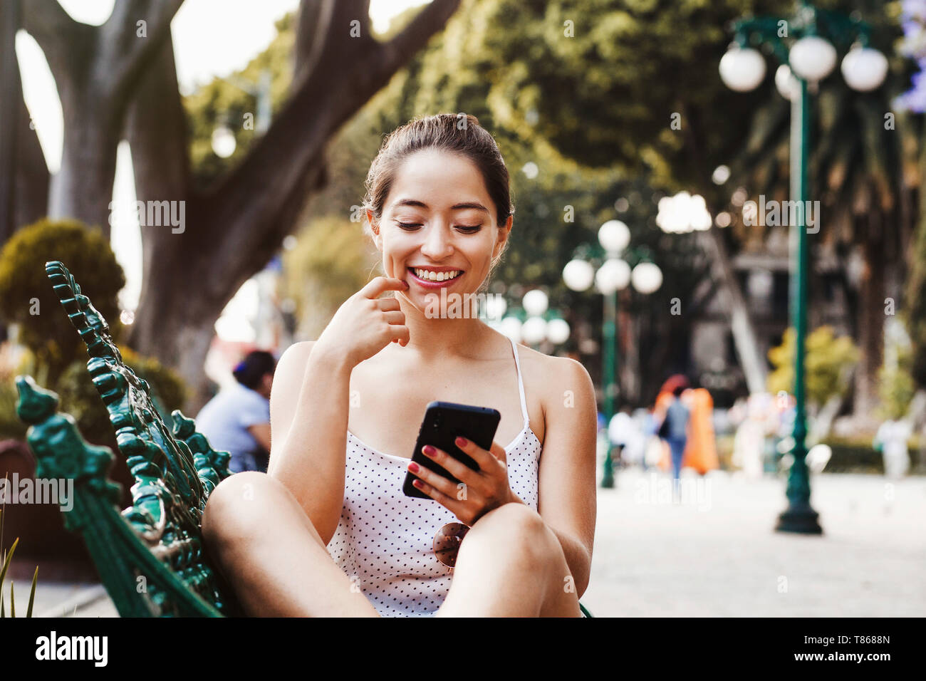 Happy Latin woman using mobile phone in latin america, mexican girl in Mexico Stock Photo