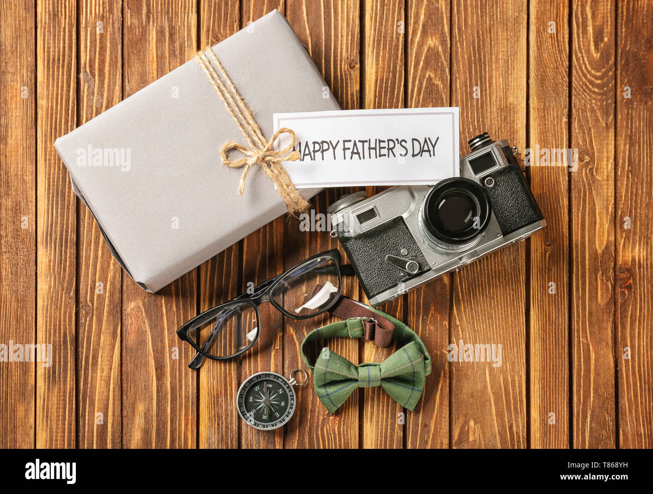 Gift box, photo camera and male accessories on wooden background. Happy Father's Day celebration Stock Photo