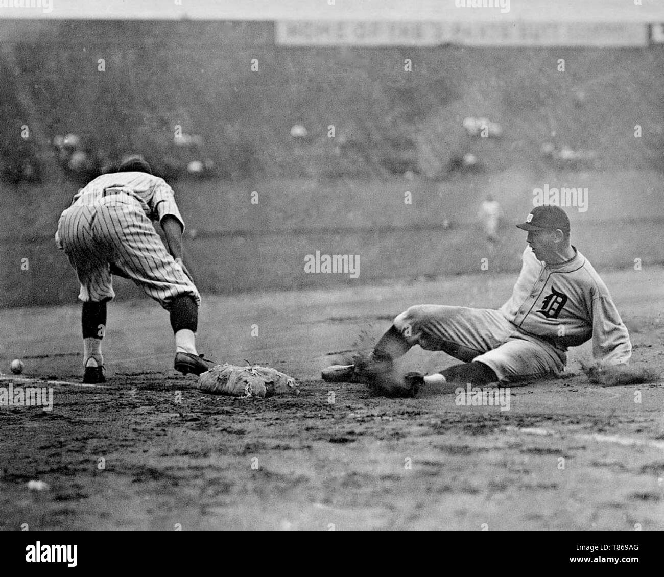 Detroit Tigers player slides safely into third base as a Washington Senators fielder reaches to the left for the ball during a baseball game 1910. Stock Photo