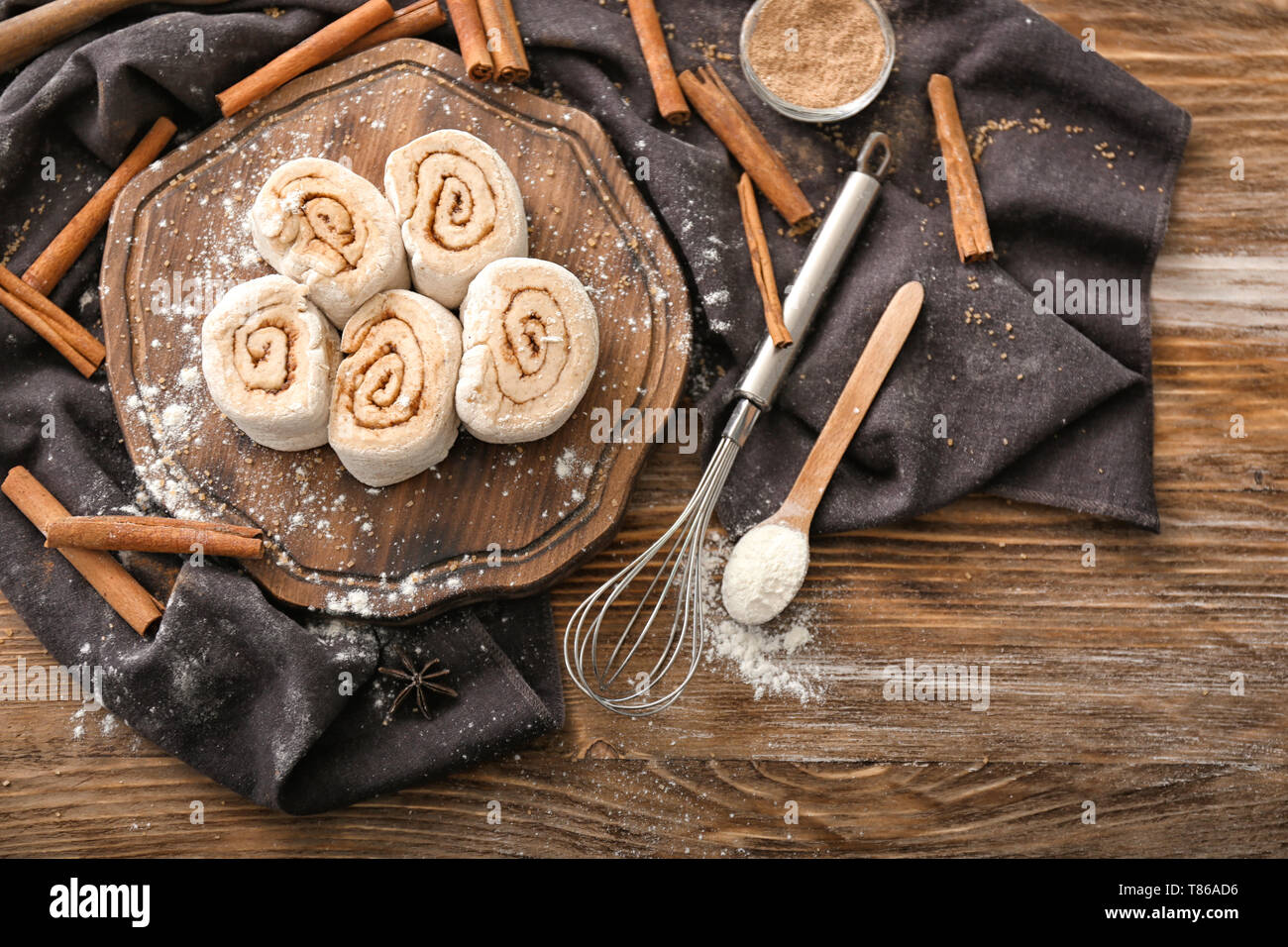 Wooden board with uncooked cinnamon rolls on kitchen table Stock Photo