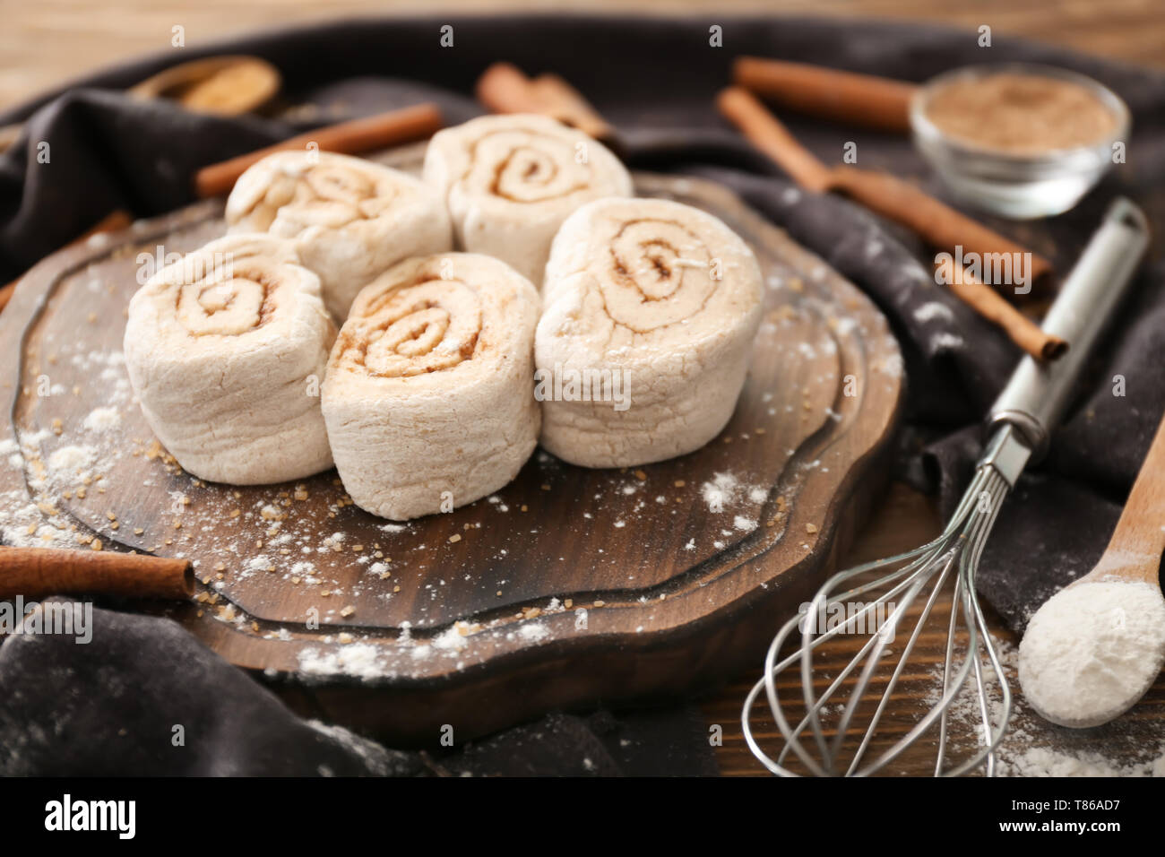 Wooden board with uncooked cinnamon rolls on kitchen table Stock Photo
