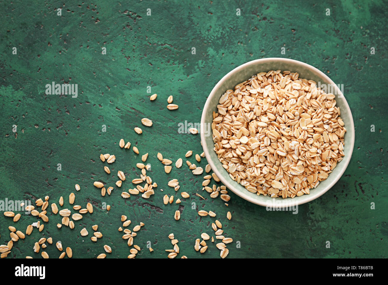Bowl with raw oatmeal on color textured background Stock Photo - Alamy