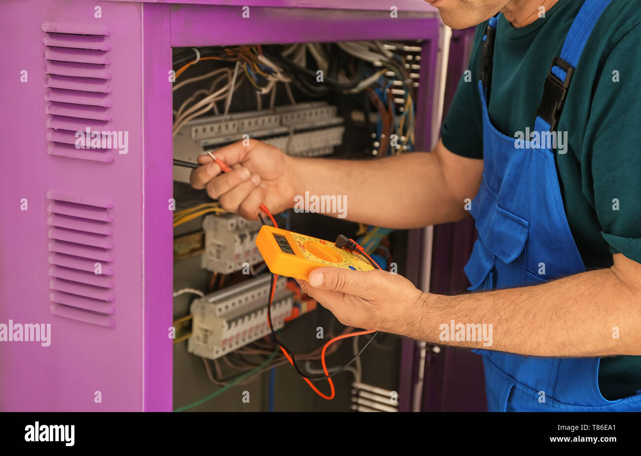 Electrician measuring voltage in distribution board Stock Photo