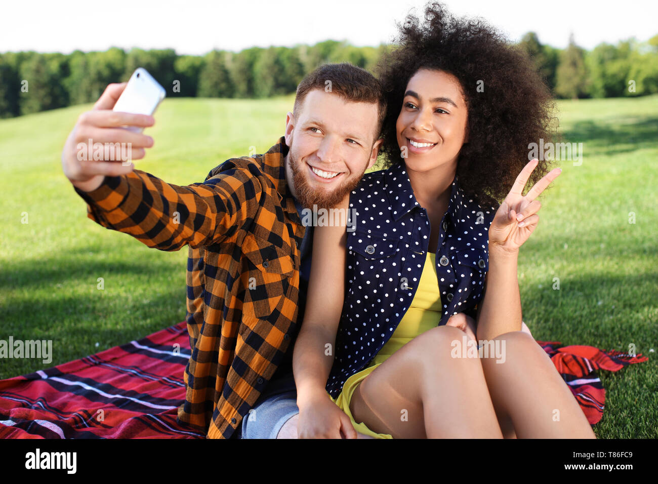 Young loving interracial couple taking selfie outdoors on spring day Stock Photo
