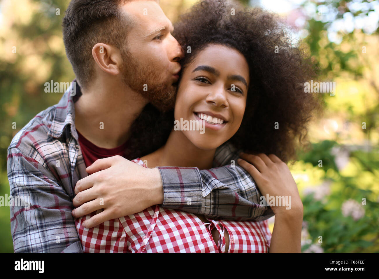Young loving interracial couple in park on spring day Stock Photo