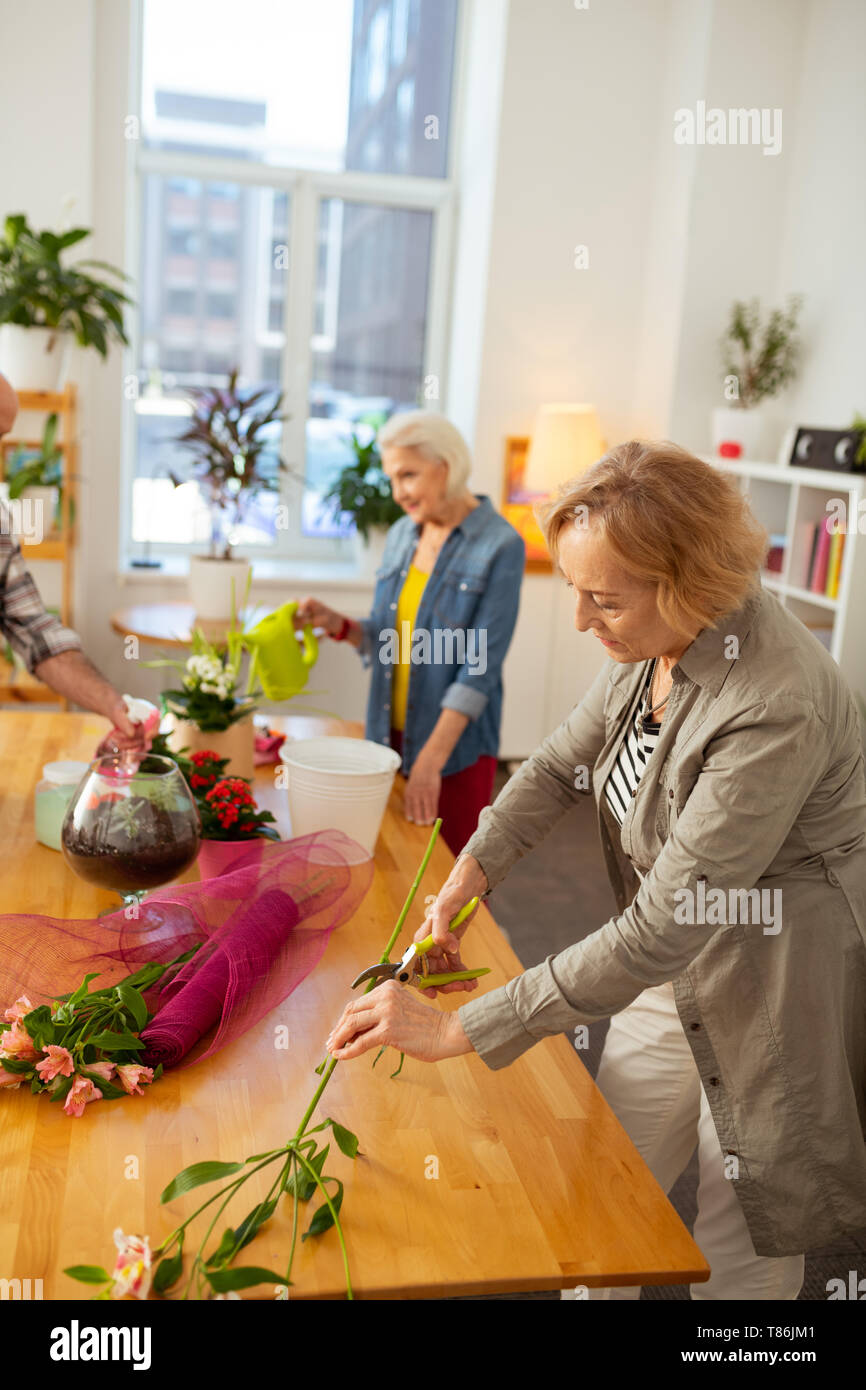 Pleasant senior woman holding a flower branch Stock Photo