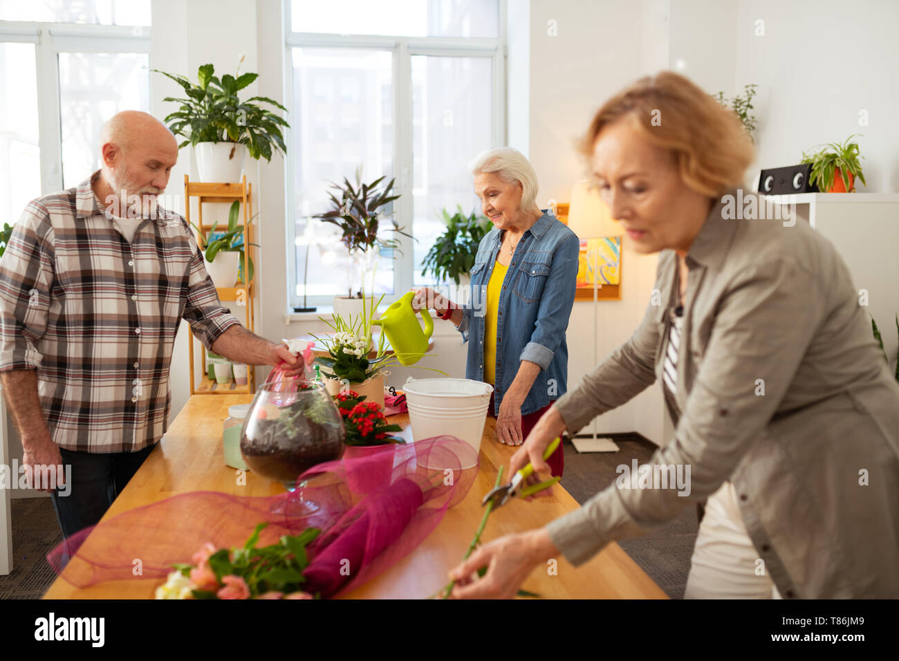 Pleasant elderly people being engaged in floristry Stock Photo