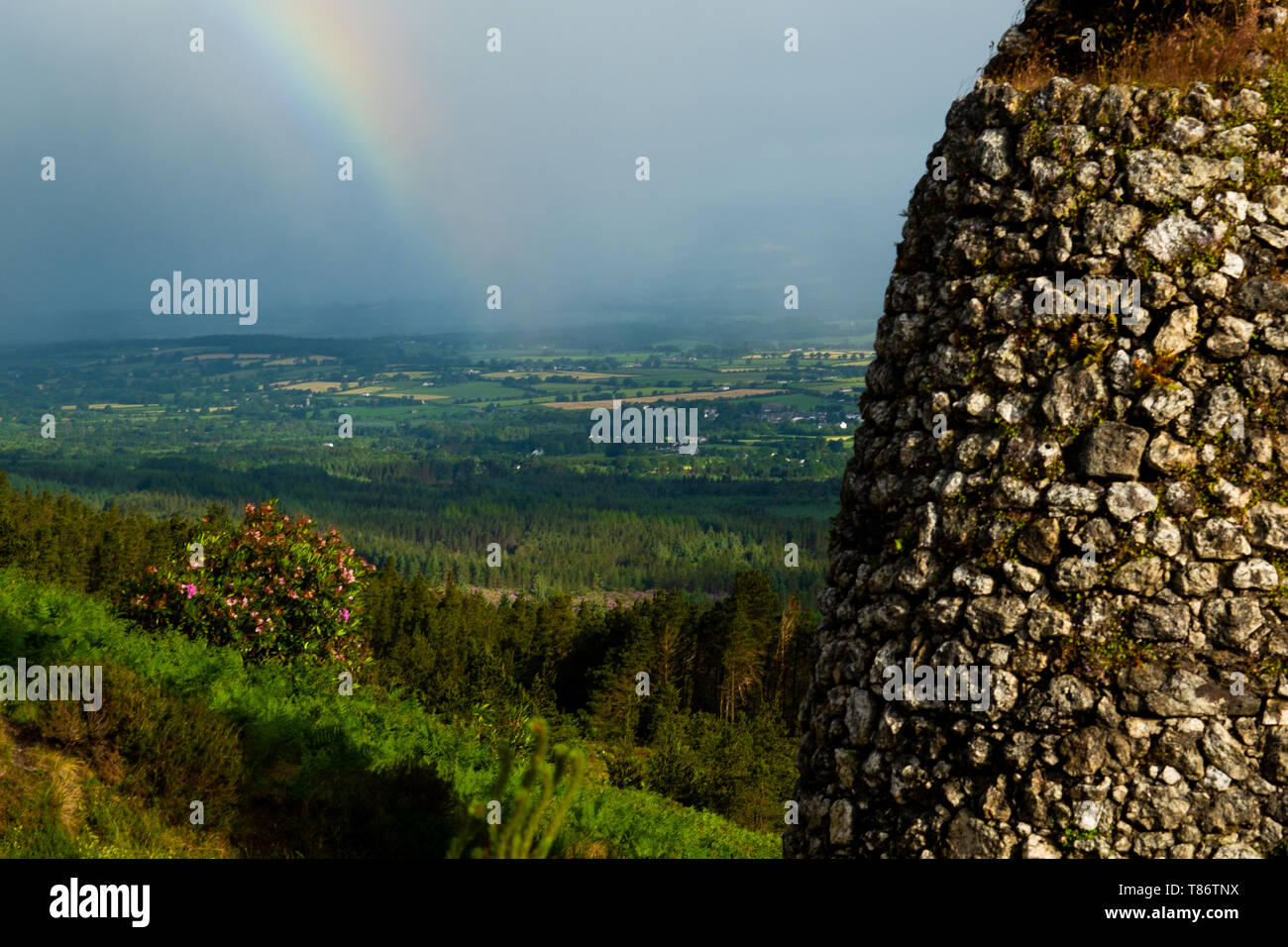 Grubbs monument in The Vee, Country Tipperary, Ireland, with an approaching summer rain storm and rainbow in the valley. Stock Photo