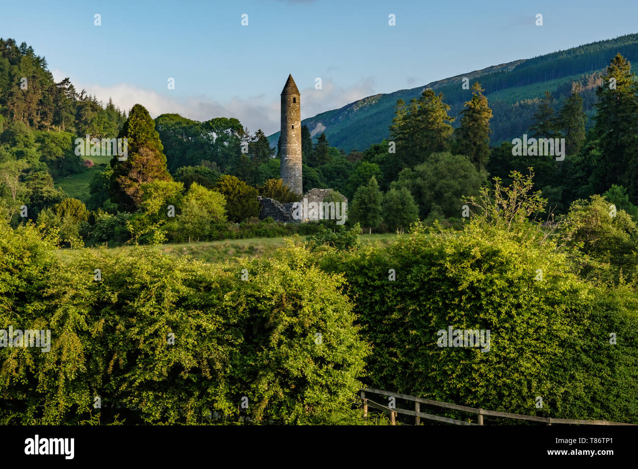 Round tower at the Glendalough ancient monastic site in Ireland receiving the morning sunrise. Stock Photo
