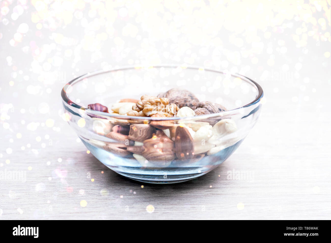 Almonds, Hazelnuts, Cashew Nuts and Whole Walnuts in a Glass Bowl. Round Golden Soft Lights. Healthy Organic Snack, Breakfast, Food Ingredients Concep Stock Photo