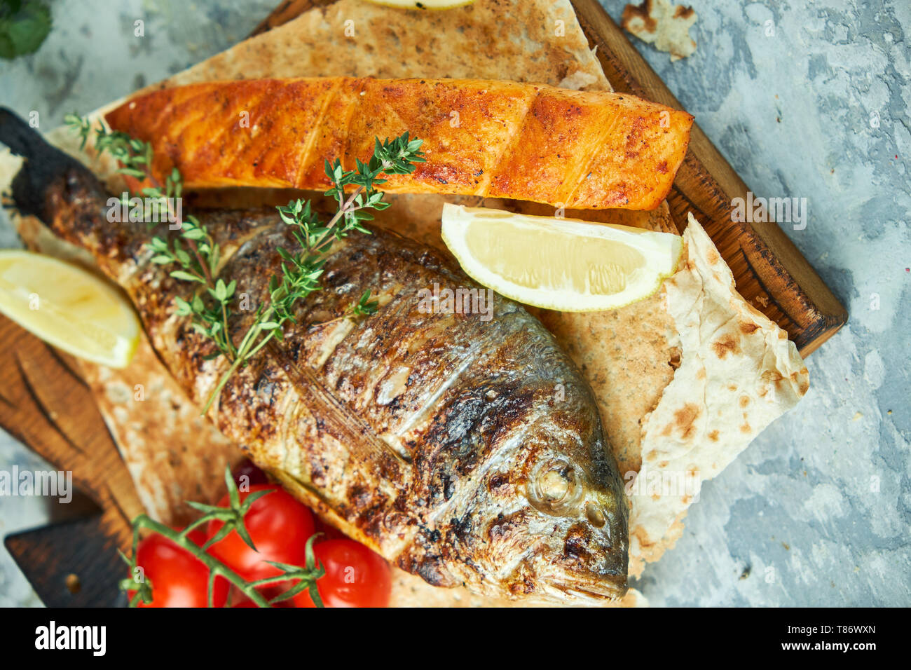 Grilled Dorado Fish And Salmon Steak On A Wooden Board With