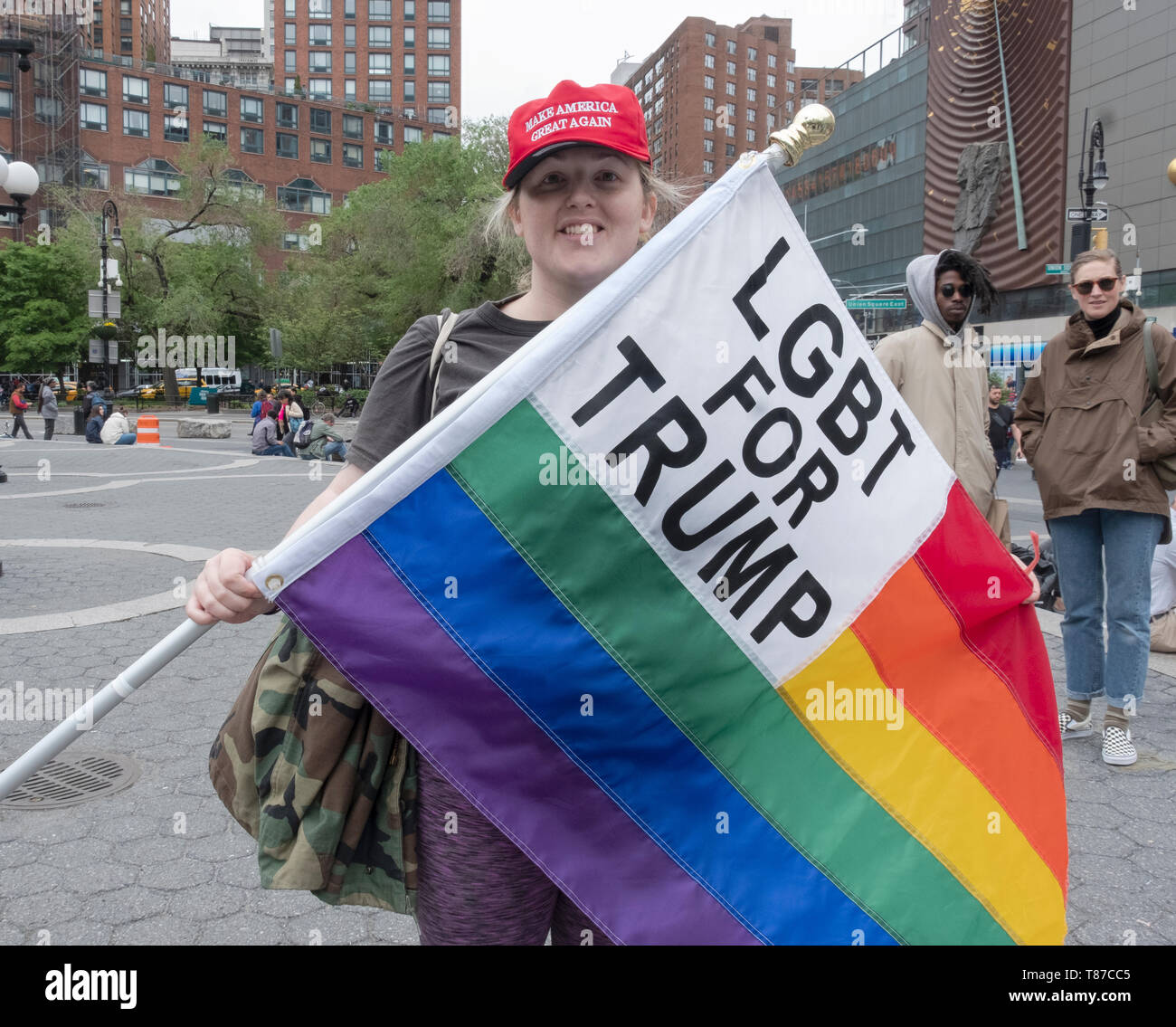 A transgender woman wearing a MAGA hat and holding and LGBT FOR TRUMP rainbow flag. In Union Square Parkin Manhattan. Stock Photo