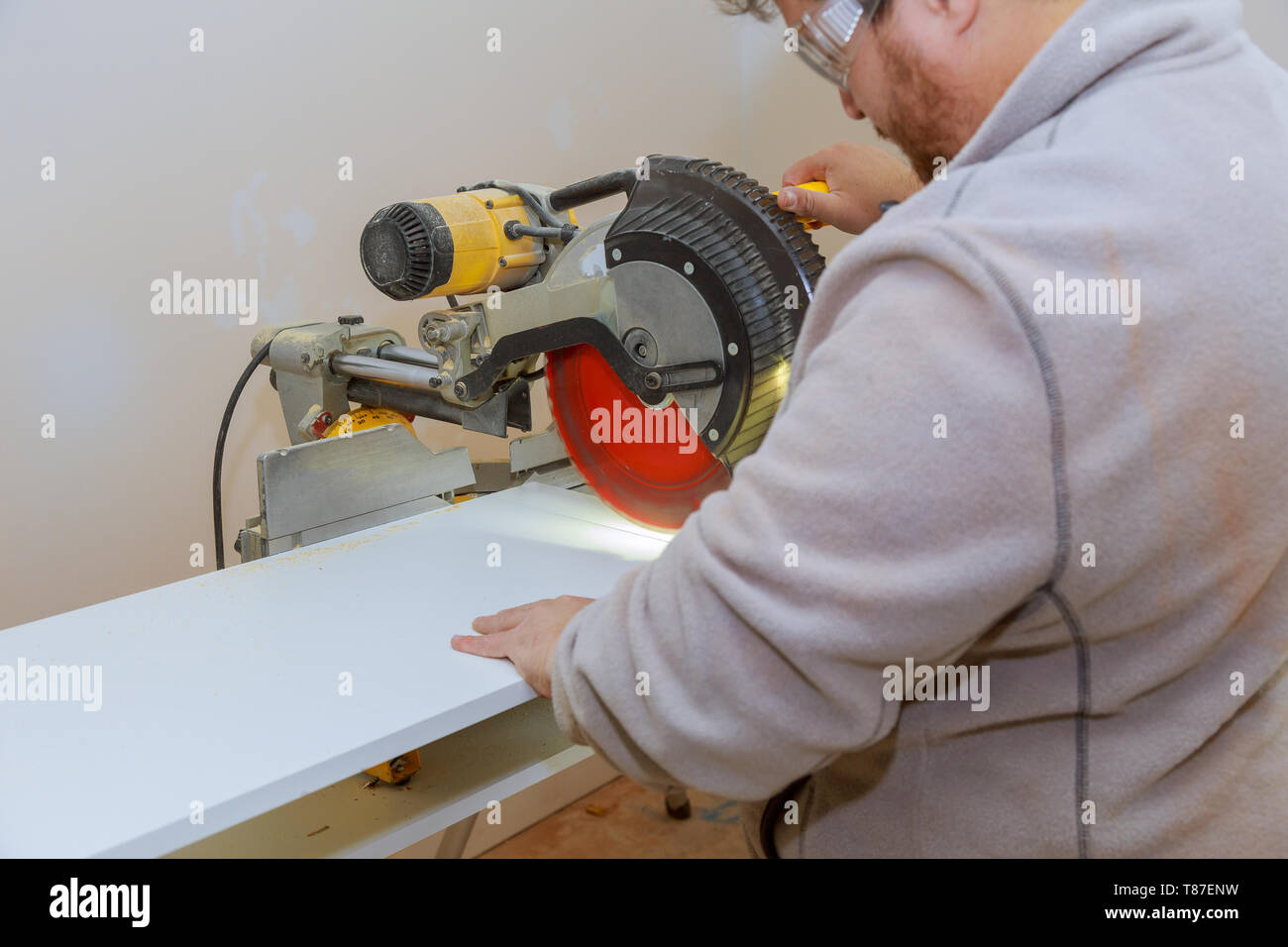 Man carpenter using circular electro saw cutting laminated white