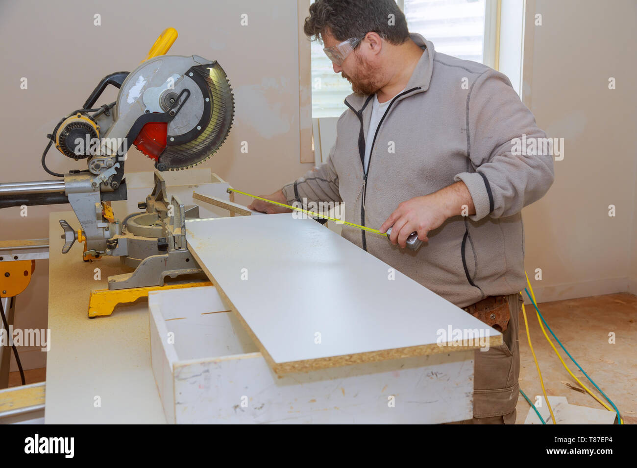 Workers installing laminate and measuring laminated white shelves