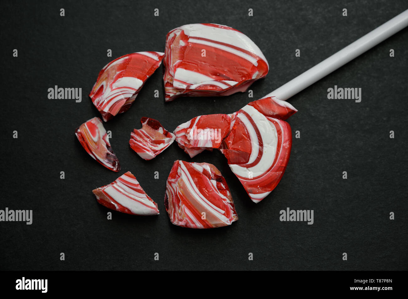 Broken lollipop on a dark background Stock Photo - Alamy