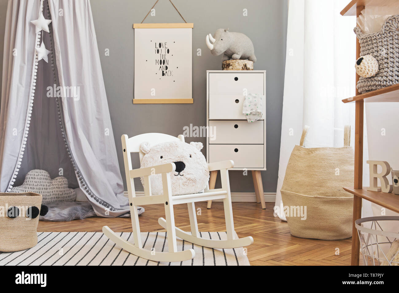 Stylish and modern scandinavian nursery interior with gray walls, brown