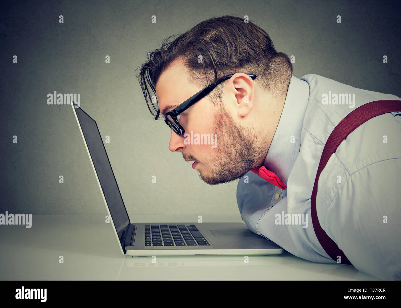 Side view of a chubby man with bad vision having difficulty to read email Stock Photo