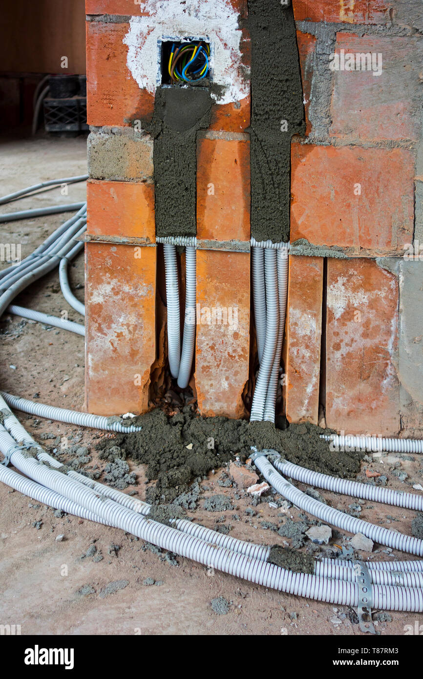 Electric wires / electrical cables / wiring on the floor to electrical outlets / power points / wall sockets in newly built house under construction Stock Photo