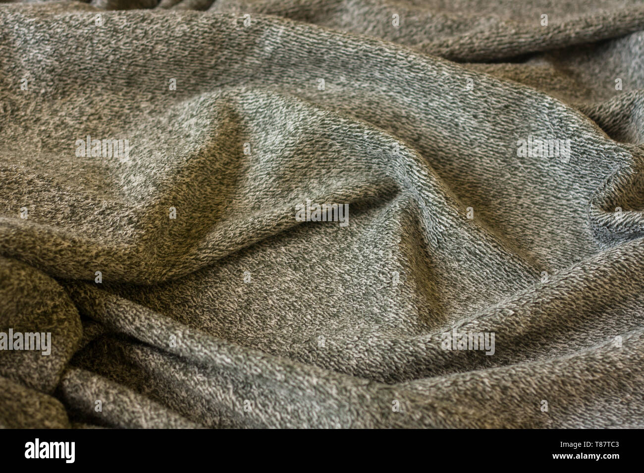 Warm fluffy grey cozy blanket. Texture of material with folds. Stock Photo