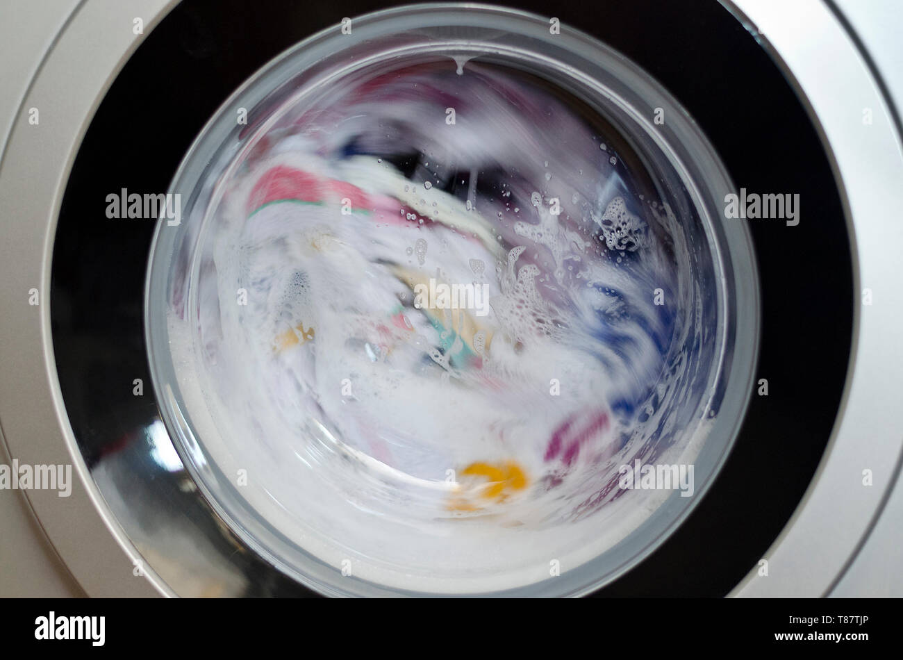 Washing machine door with rotating garments inside Stock Photo Alamy