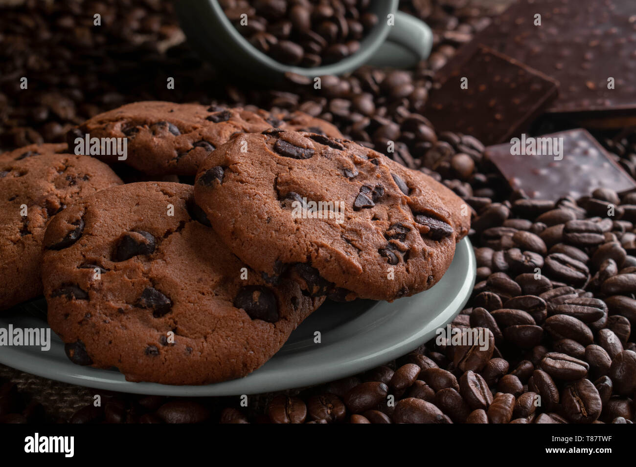 on coffee beansthe cup lies from it gets enough sleep coffee, opposite a chocolate bar, there are cookies behind Stock Photo