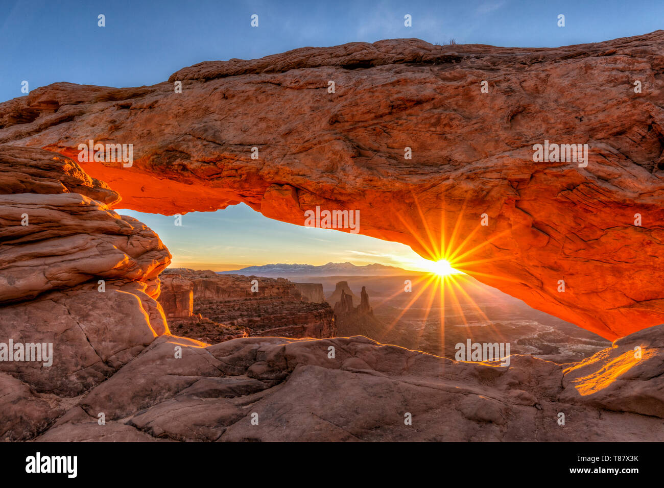 A sunburst peaks out through Mesa Arch in Canyonlands National Park, Utah Stock Photo