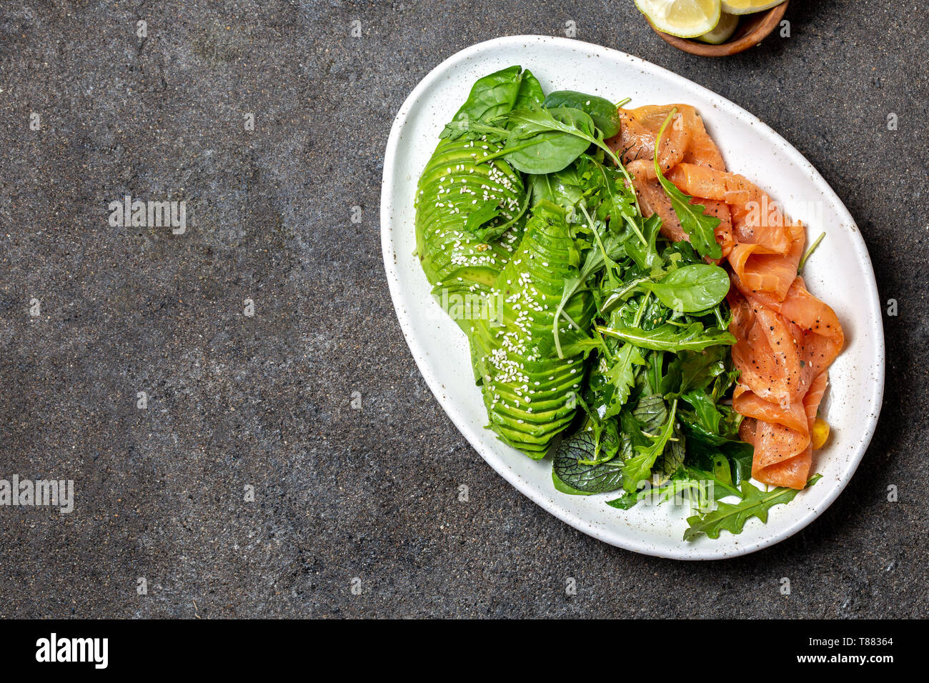 Low carbs salad. Spinach, rucola salad with avocado and salmon. Black