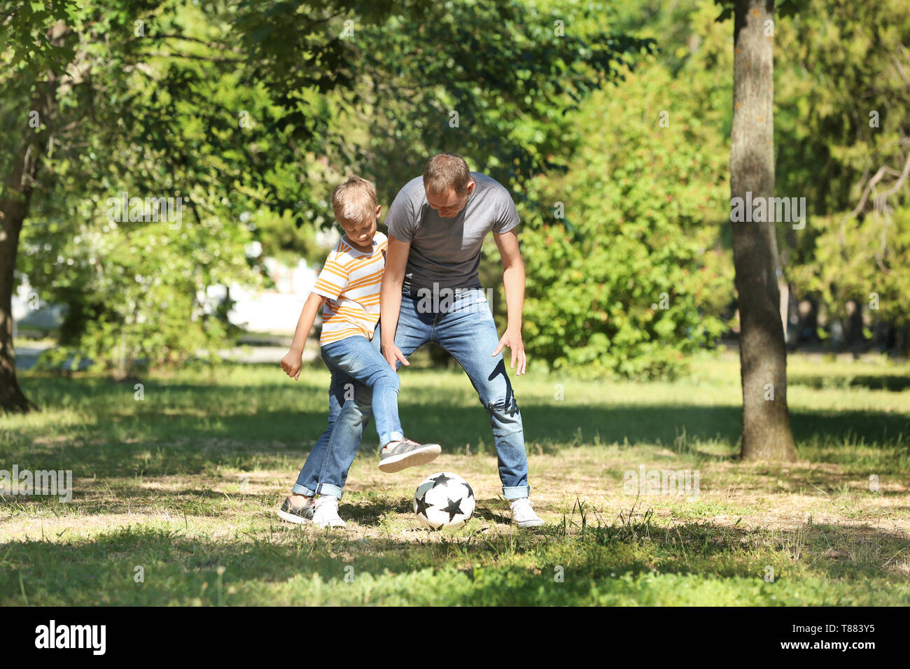 Happy father and son playing football in park Stock Photo - Alamy