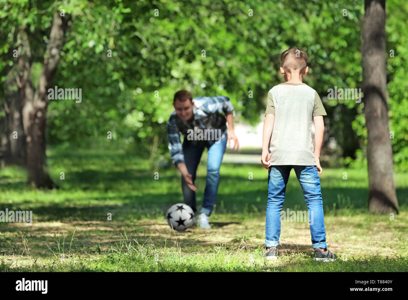 Happy father and son playing football in park Stock Photo - Alamy
