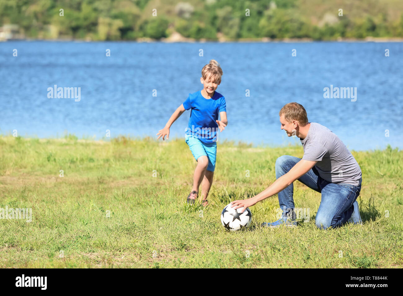 Happy father and son playing football near river Stock Photo Alamy