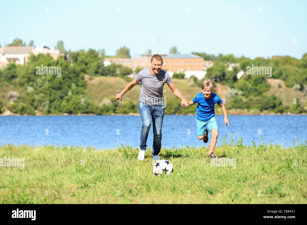 Happy father and son playing football near river Stock Photo Alamy