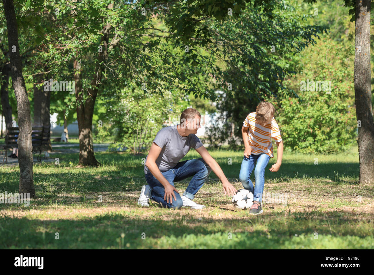 Happy father and son playing football in park Stock Photo - Alamy