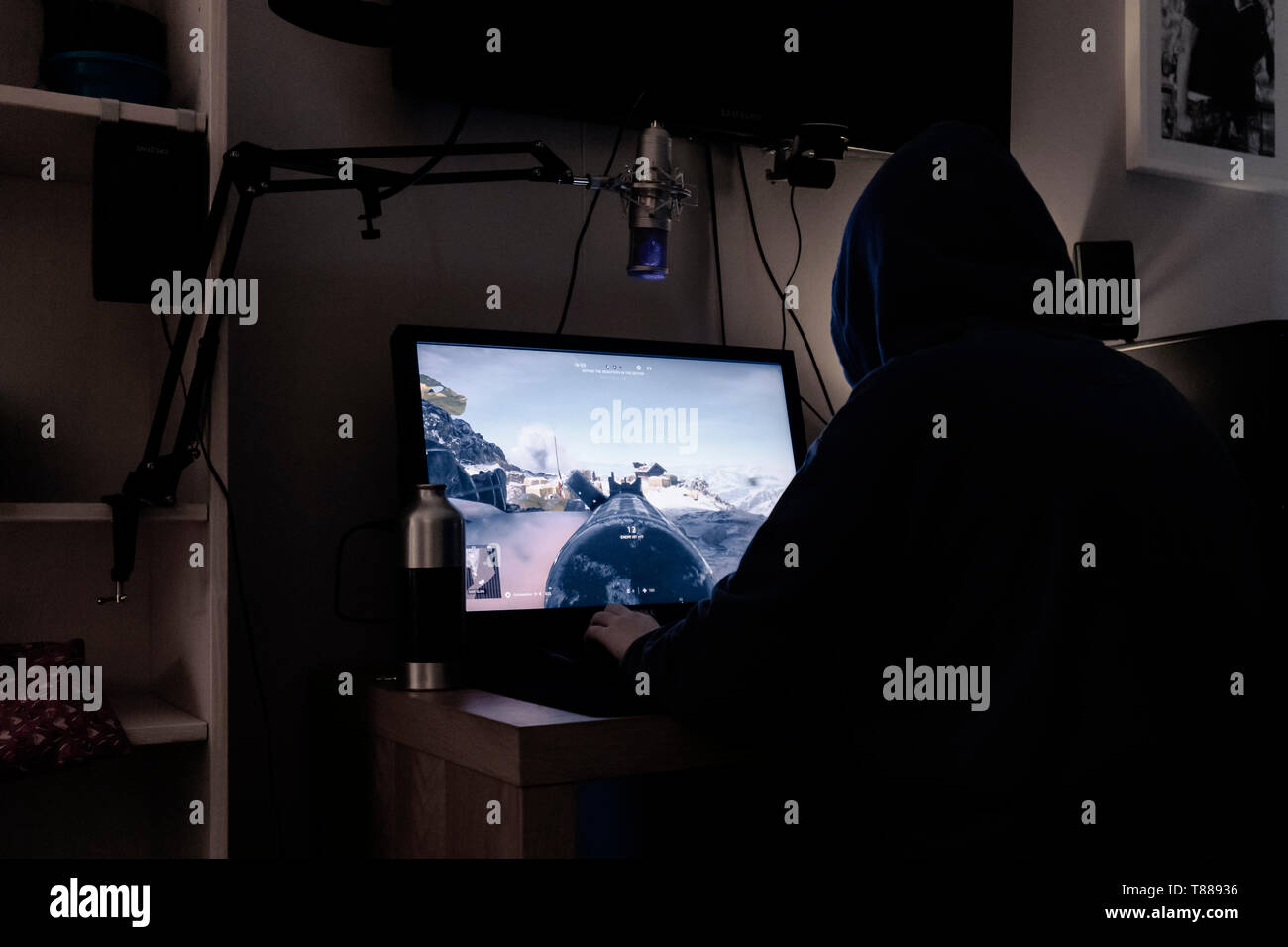 Teenager sitting in the dark gaming on desktop computer Stock Photo