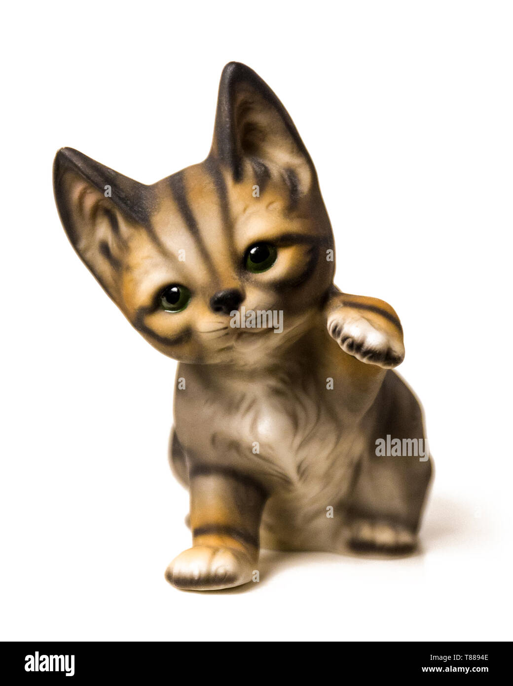 Porcelain kitten lifting it's paw figurine cut out isolated on white background Stock Photo